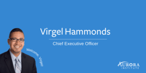Headshot of Virgel. He is wearing glasses, a black blazer, light blue shirt and tie. Photo reads: "Virgel Hammonds, Chief Executive Officer, Aurora Institute. Welcome Virgel!"